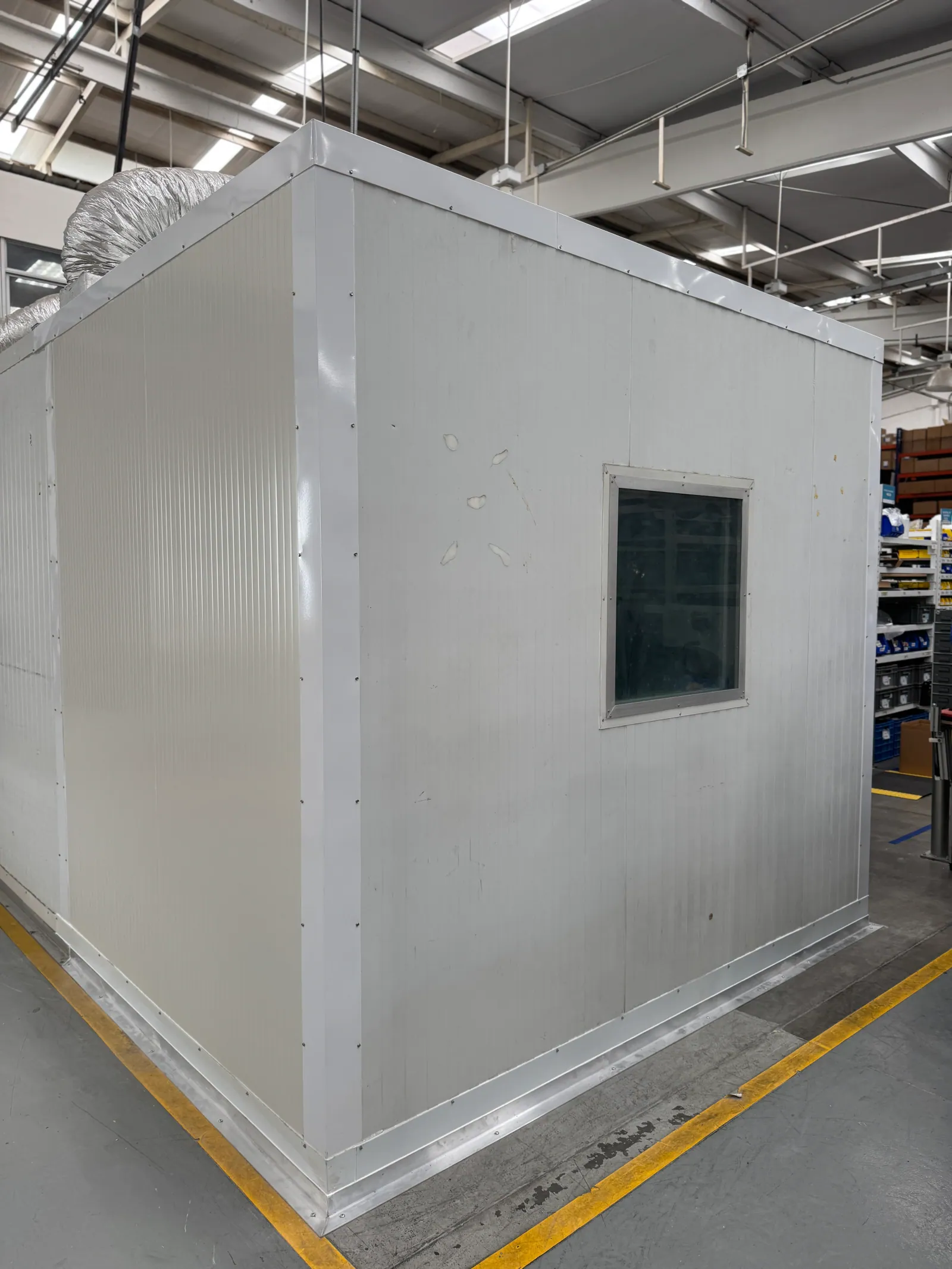 Exterior del cuarto acústico montado dentro de la planta, con ventana y ducto de ventilación